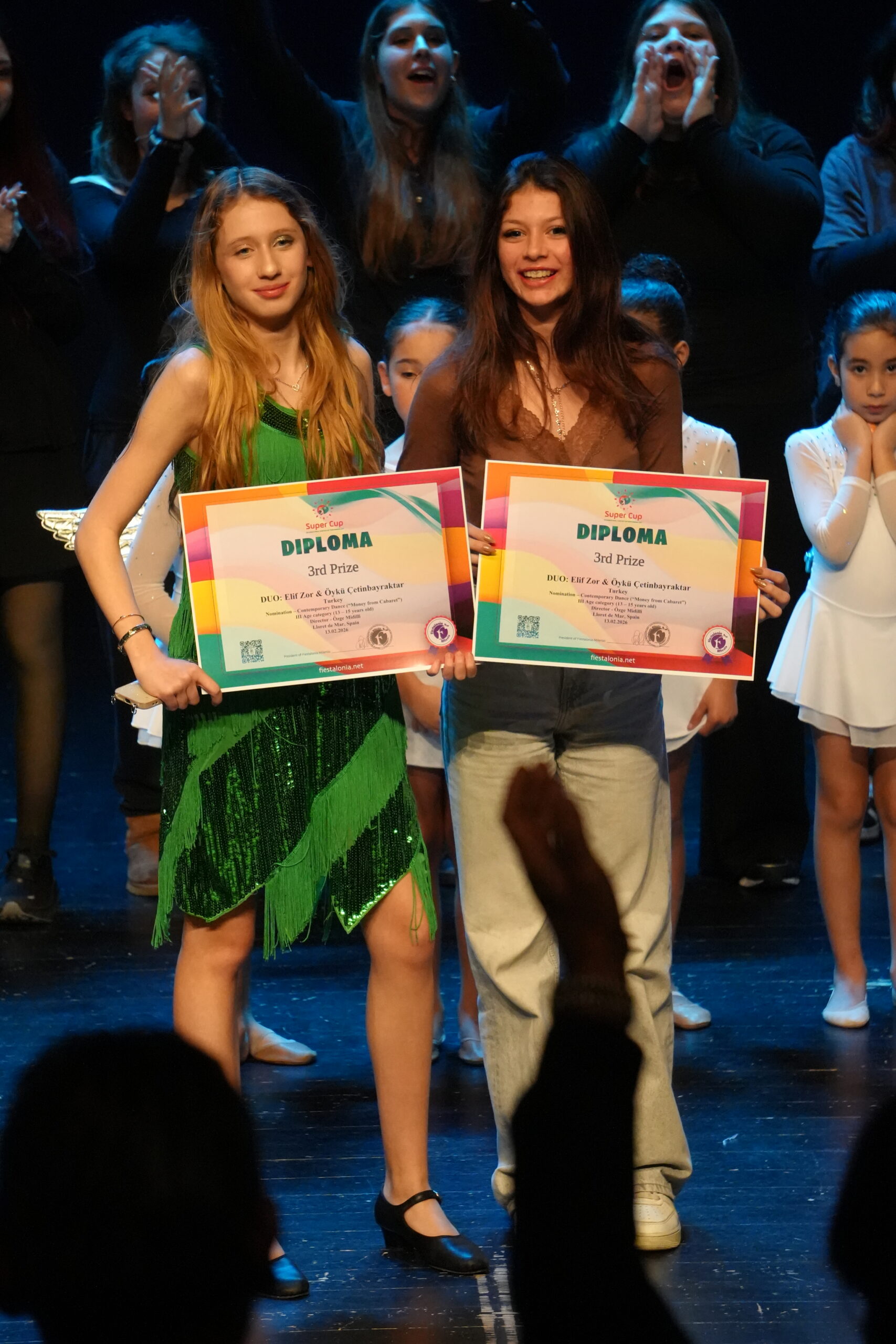Two Super Cup participants holding diplomas, archive 2026.